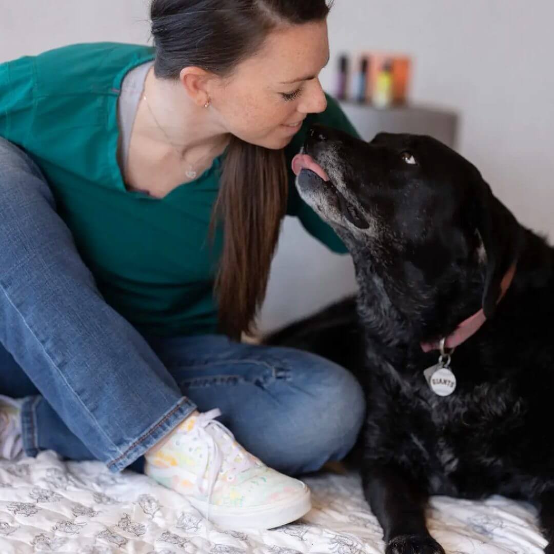 Vet tech kissing old dog 